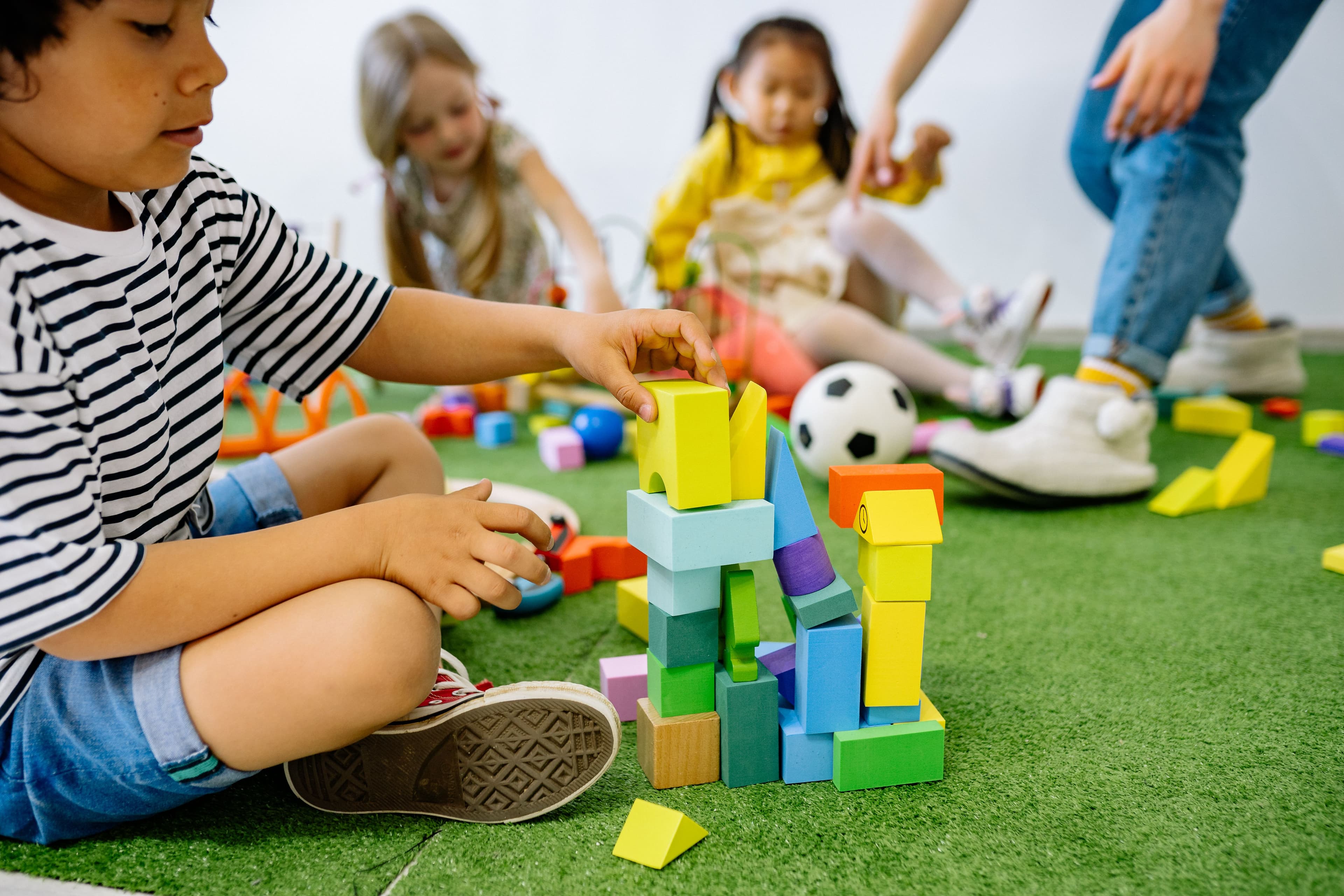 School-age child building a tower with colorful blocks in a playroom